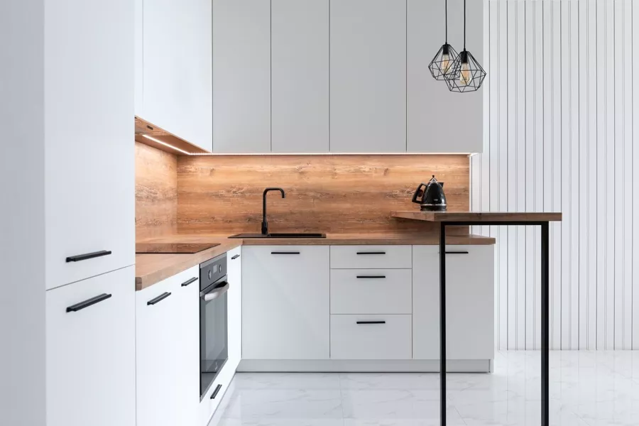 Weiße matte Einbauküche mit Holz-Rückwand als Beispiel für eine mittlere Preisgruppe