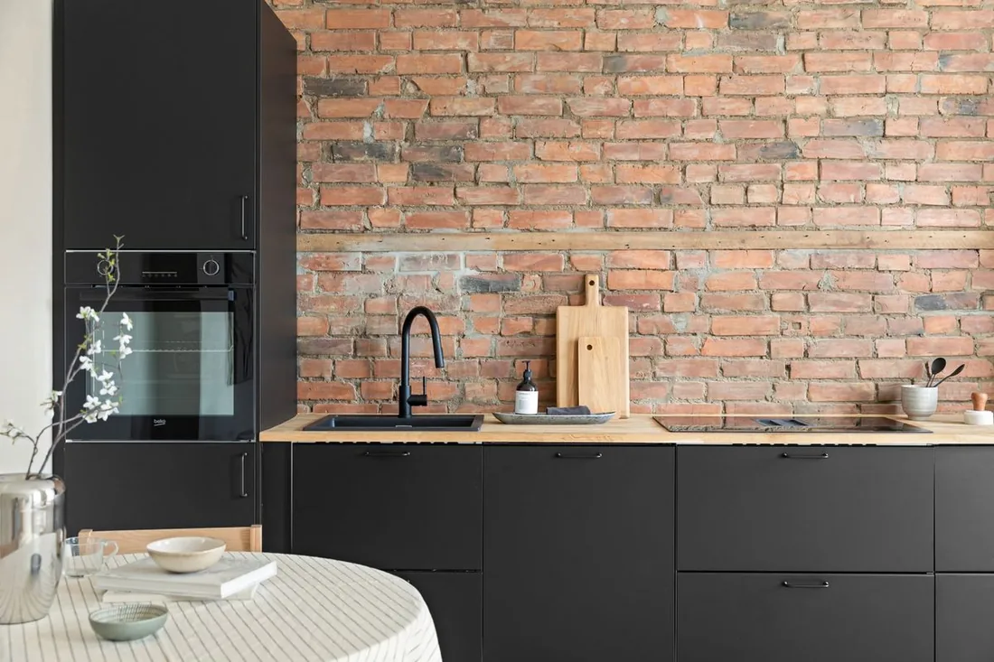 Person misst mit Zollstock die Maße einer Küchenzeile für die Passform-Prüfung