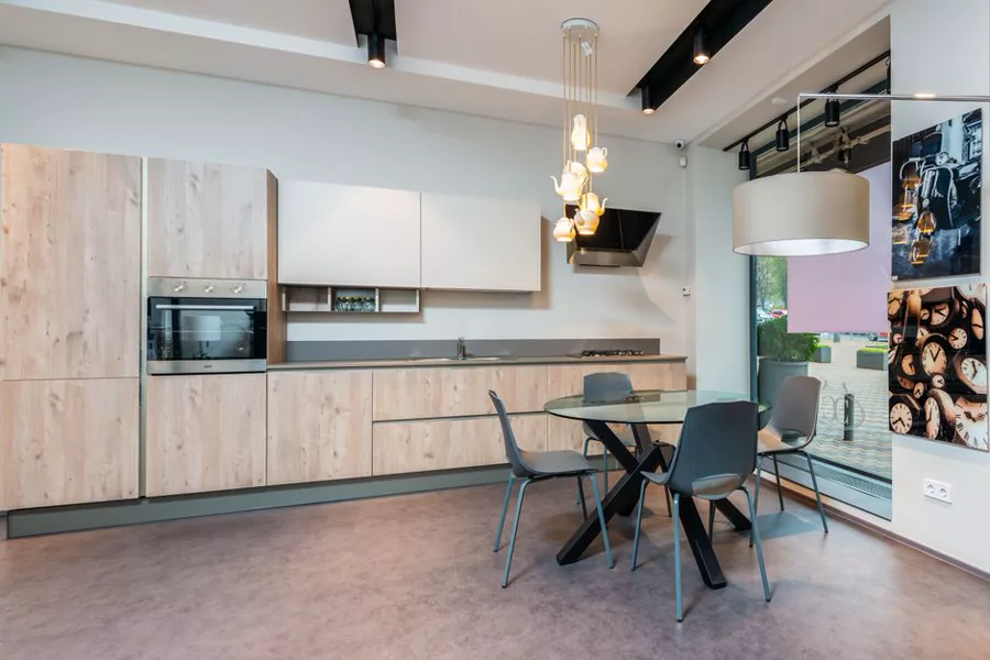 Helle Ausstellungsküche aus Holz mit Esstisch und Backofen in einem Küchenstudio